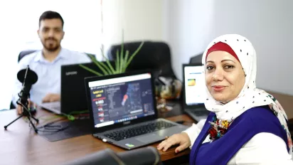 Woman sitting at computer across from male co-worker