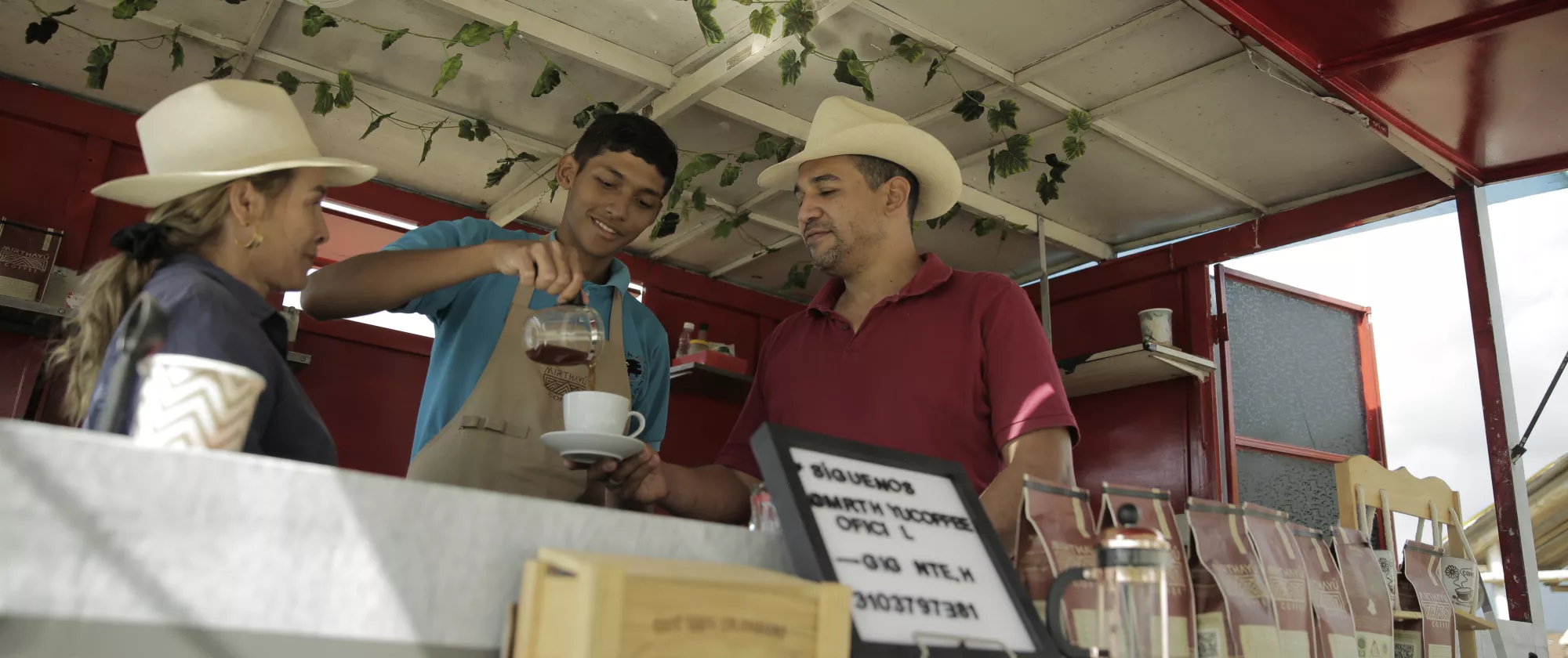 Familia cafetera, madre, padre e hijo sirviendo una taza de café en su negocio de café