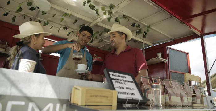 Familia cafetera, madre, padre e hijo sirviendo una taza de café en su negocio de café