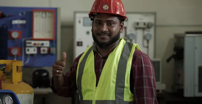 A Bangladeshi man in protective gear shows thumbs up sign