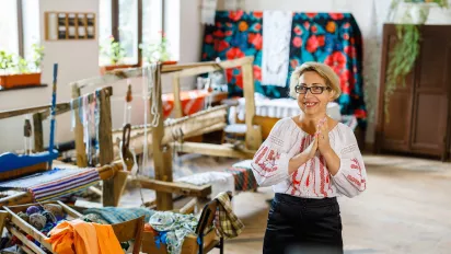 A women standing by a sewing machine in her embroidery workshop.