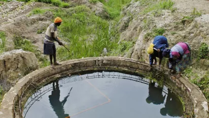 Men standing around a water reservoir used for crop irrigation in Rwanda