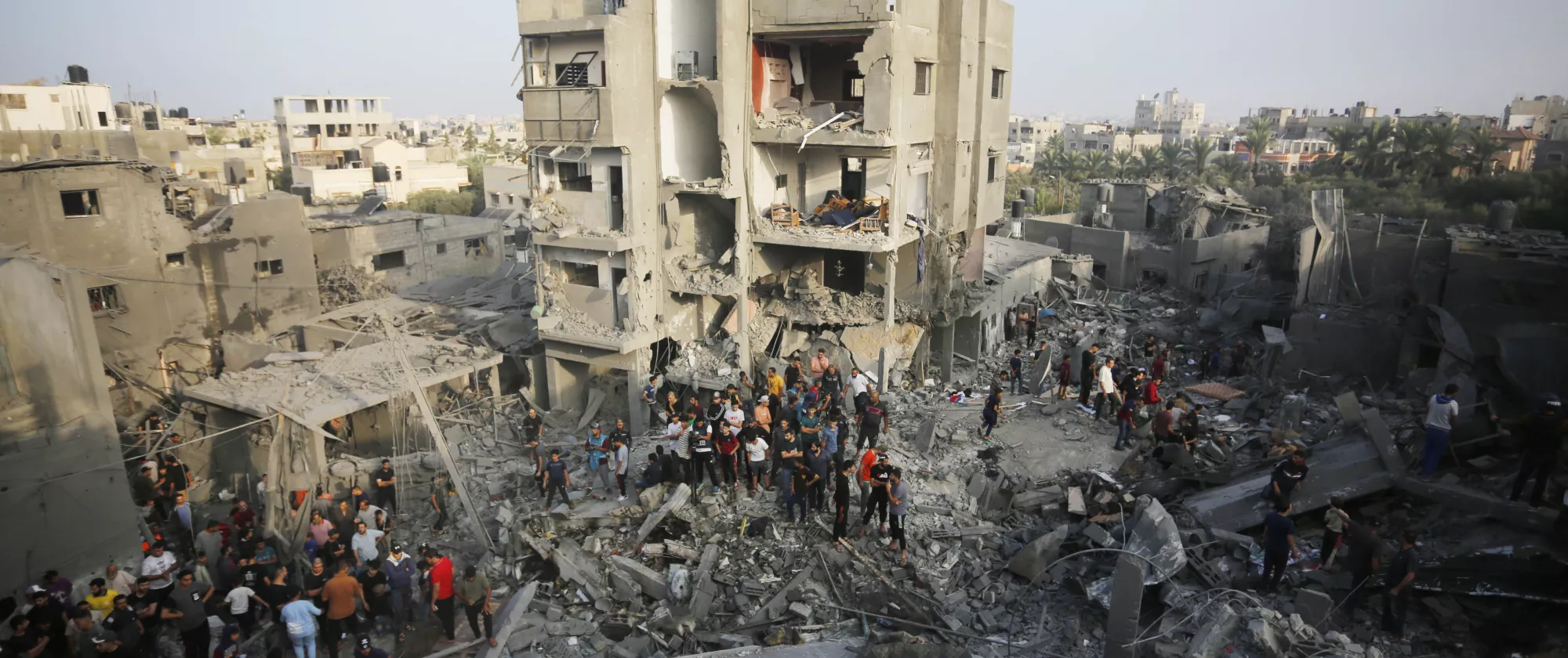 a group of people standing on rubble of demolished buildings 