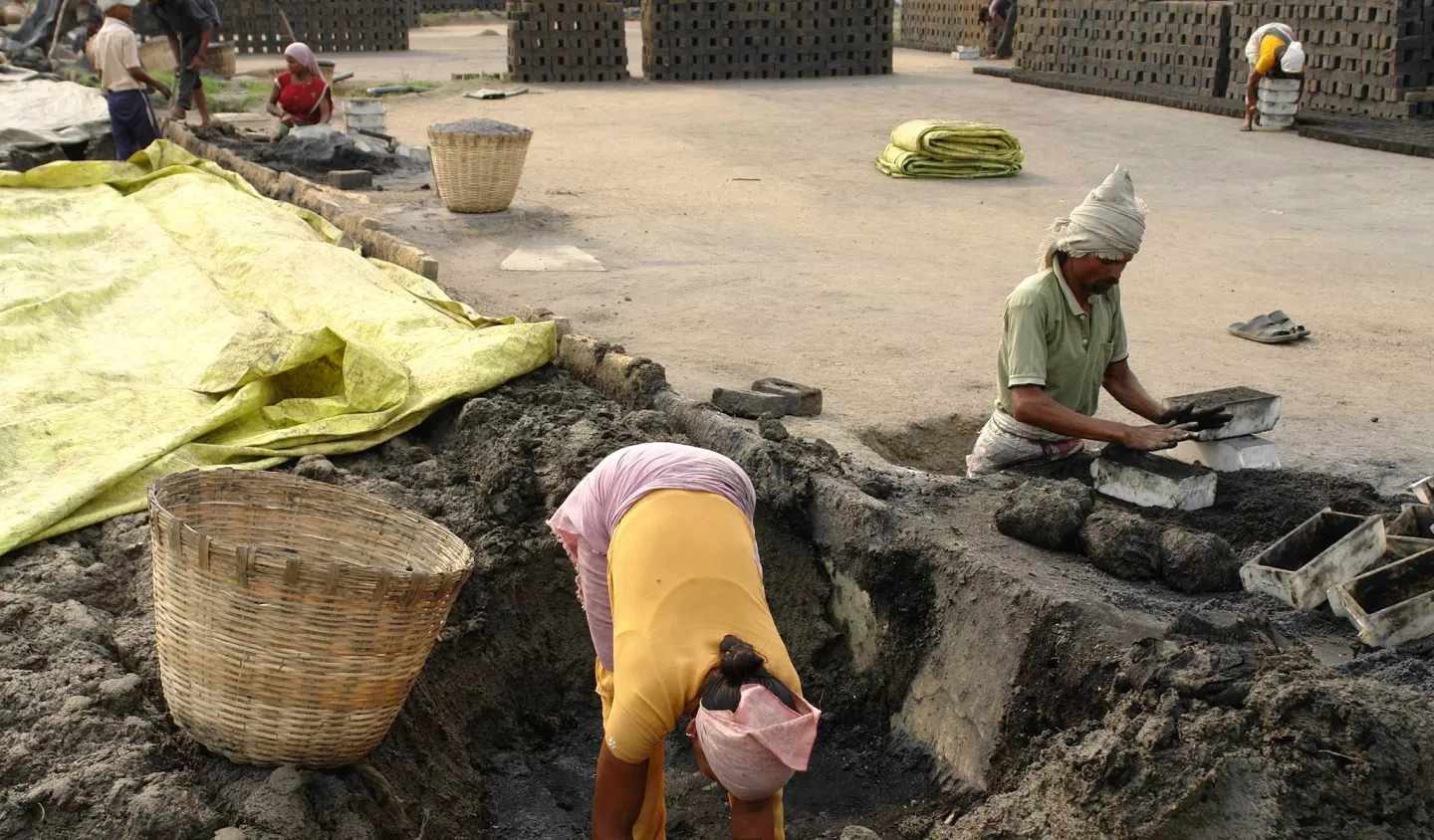 Two workers in debt bondage at a brickworks in India digging in the earth to make bricks