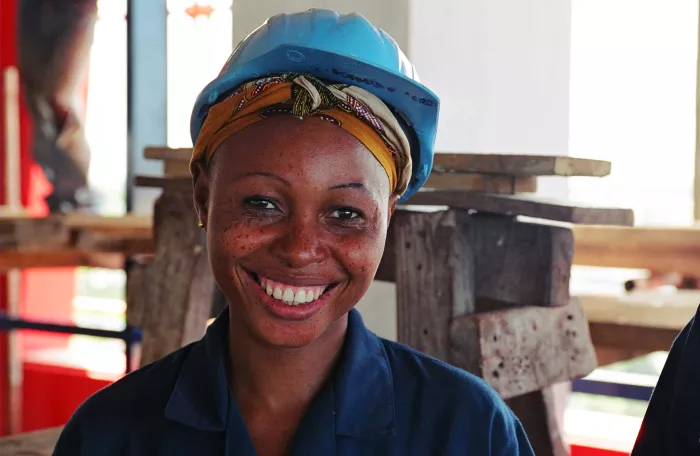 A smiling woman with a hard hat.