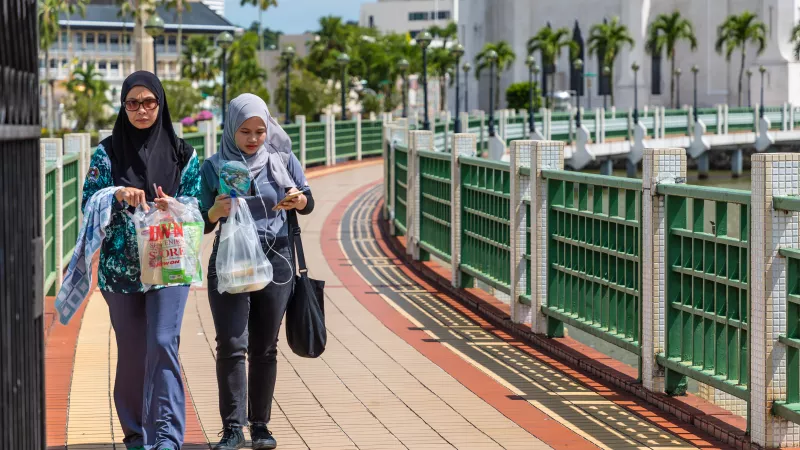 Brunei ladies walking on a bridge in front of a mosque