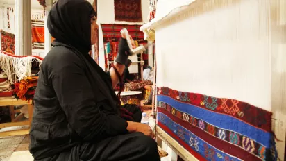 Iraqi woman weaving a carpet.