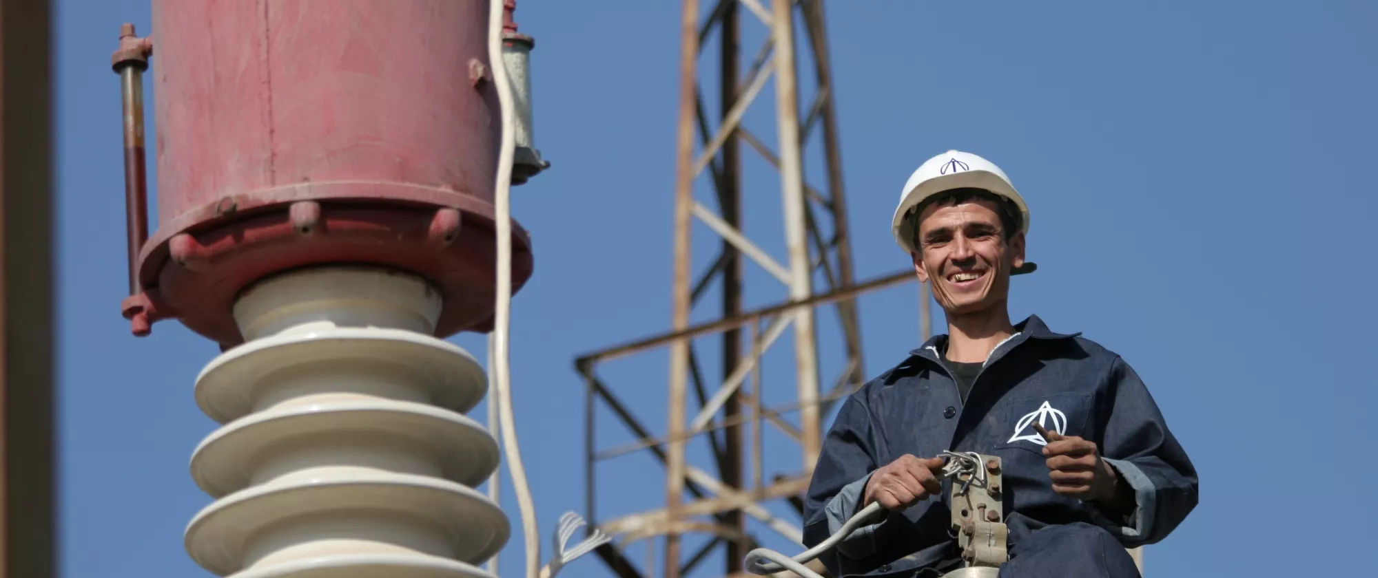 Man in helmet and overalls works with machinery on a site.