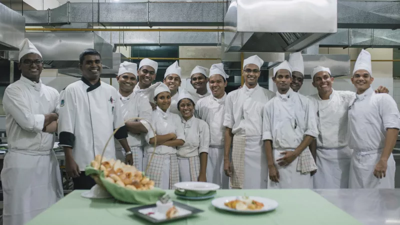 Group of trainee chefs stand facing the camera