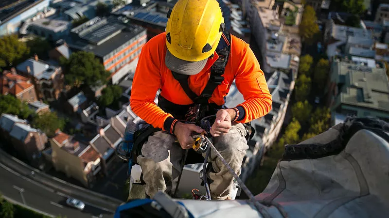 A rope access jobs worker with safety equipments working at high rise construction building site in Sydney, Australia